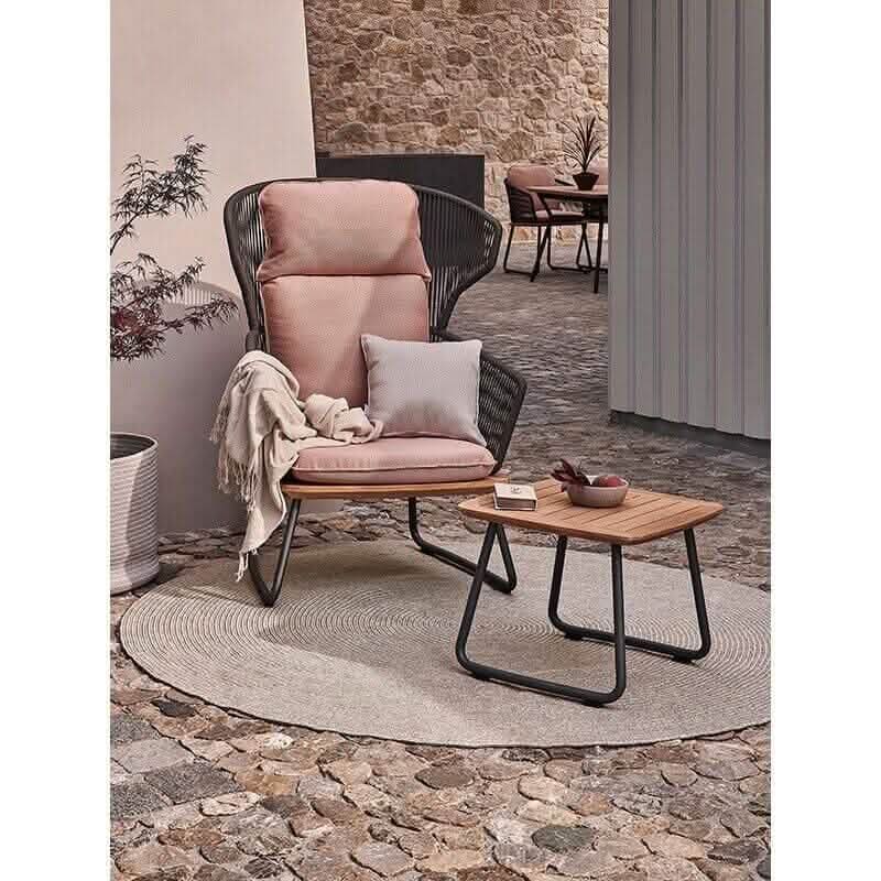 Der runde Weishäupl Outdoor-Teppich in Sand auf einer Holzterrasse mit modernen Gartenmöbeln.